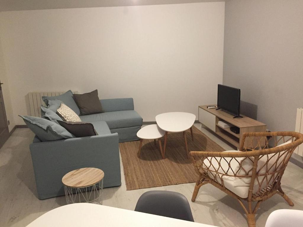 a living room with a blue couch and a tv at Maison Cosy centre de Pouzauges in Pouzauges