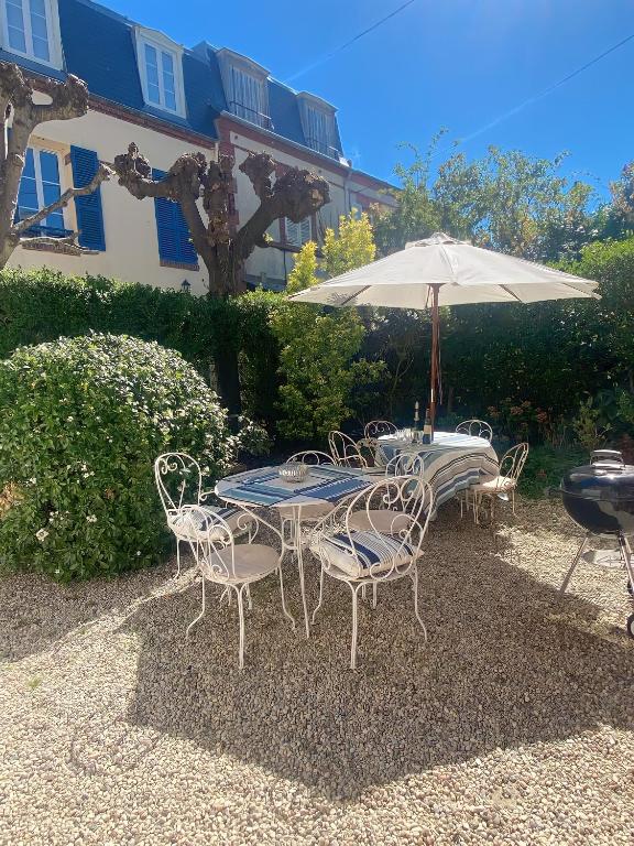 - une table et des chaises avec un parasol dans la cour dans l'établissement Maison familiale hyper centre avec patio 6-7pers, à Villers-sur-Mer
