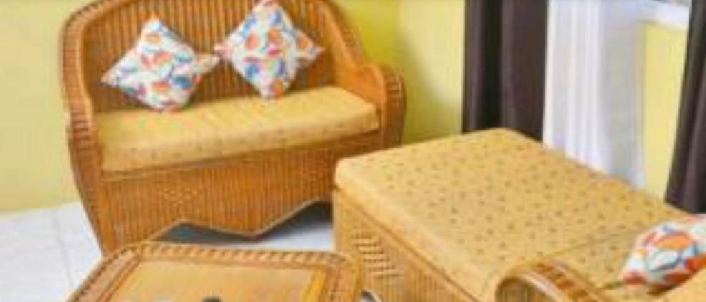 a living room with a wicker chair and a table at Essentials Suite in Bon Accord