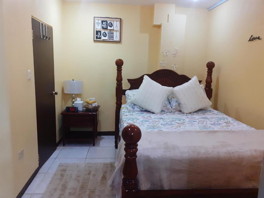 a bedroom with a wooden bed with white pillows at Essentials Suite in Bon Accord