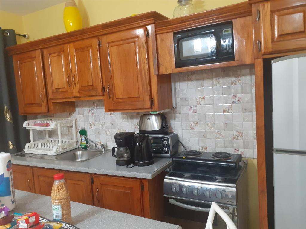 a kitchen with wooden cabinets and a stove and a microwave at Essentials Suite in Bon Accord