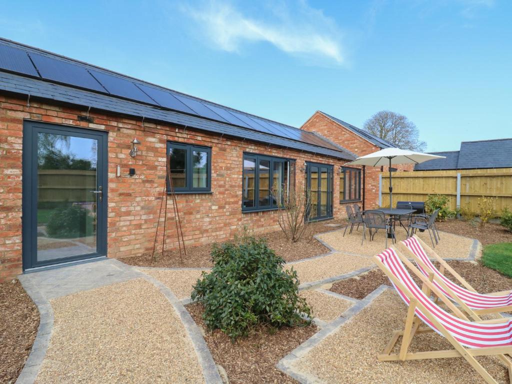 ein Backsteinhaus mit zwei Stühlen und einem Tisch in der Unterkunft Barley Cottage in Huntingdon