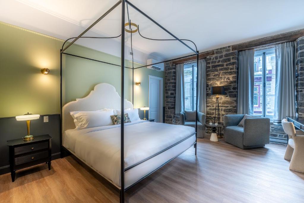 una camera da letto con letto a baldacchino e sedia di Hotel Acadia a Québec
