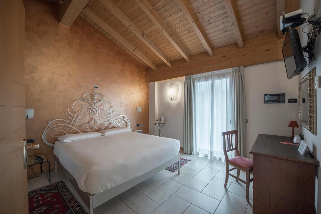 a bedroom with a bed and a desk and a television at Hotel Villa Colico in Colico