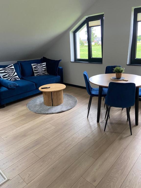a living room with a blue couch and a table at Harmony House - Appartement Blue in Kołczewo