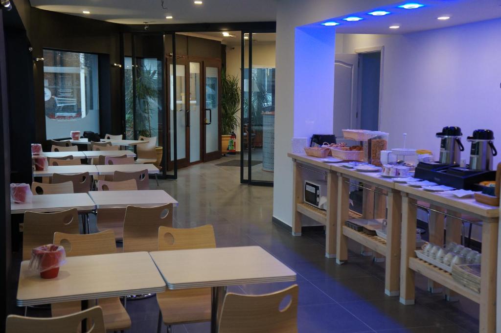 a restaurant with tables and chairs and a cafeteria at Hotel Evergreen in Brussels