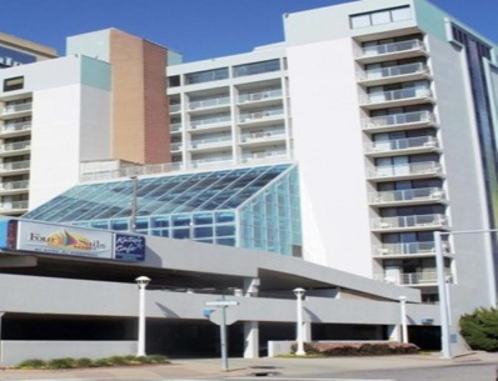 a large building with a parking lot in front of it at Four Sails Resort by VB Rentals in Virginia Beach