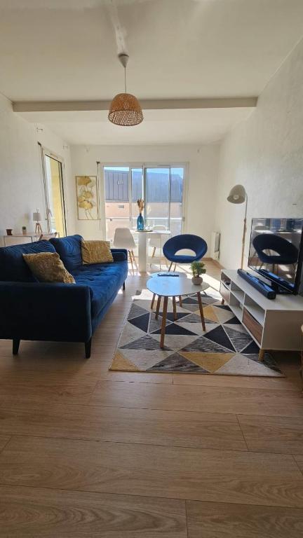 un salon avec un canapé bleu et une table dans l'établissement Hyper Centre Apartment with Garage, au Mans