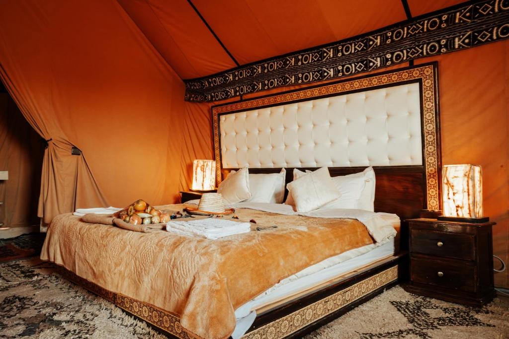 a bedroom with a large bed with an orange wall at Luxury Desert Camp in Merzouga