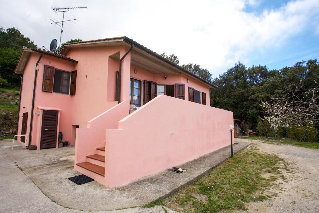 uma casa rosa com uma escada em frente em Villino Mare e Natura em Marciana Marina