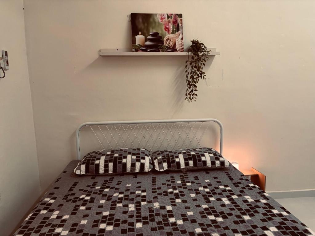 a bedroom with a bed with a black and white checkered bedspread at Homestay Selesa Taman Lembah Bujang in Bedung