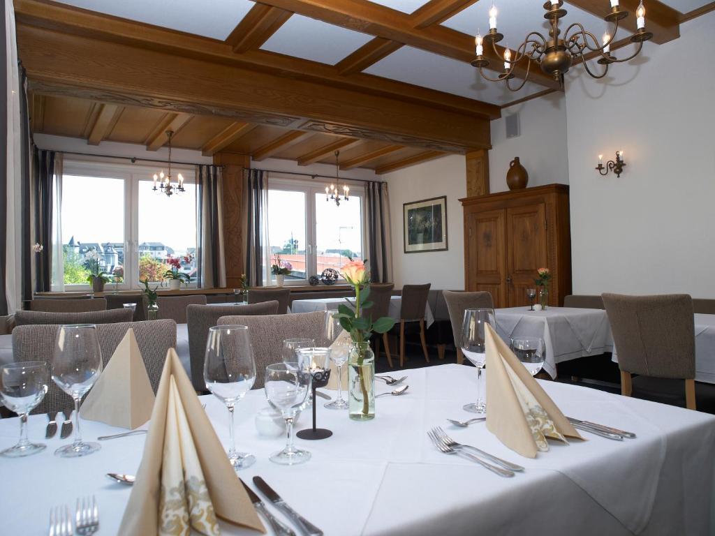 a dining room with white tables and chairs and windows at Weingutshotel Piesporter Goldtröpfchen in Piesport