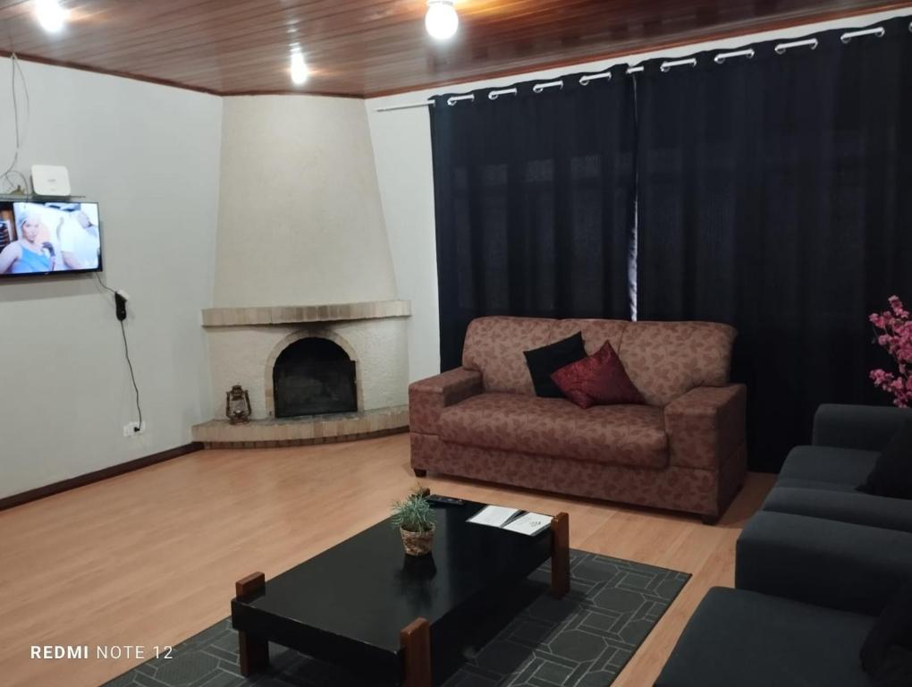 un salon avec un canapé et une cheminée dans l'établissement Recanto Benedetti, casa para temporada, à Campos do Jordão