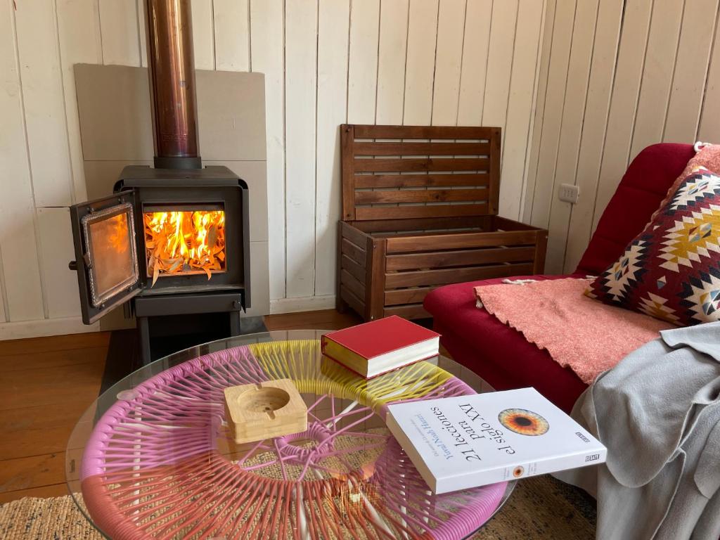 QuiñicabeにあるNaturaVista Cabins Matanza 13kmのリビングルーム(ガラステーブル、暖炉付)