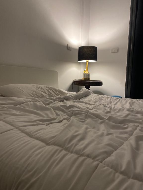 Una cama blanca con una lámpara sobre una mesa. en Vibes Master, en Madinaty
