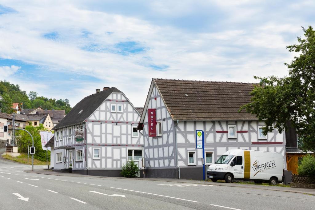 een wit gebouw met een wit busje geparkeerd naast een straat bij Hotel Werner in Mornshausen