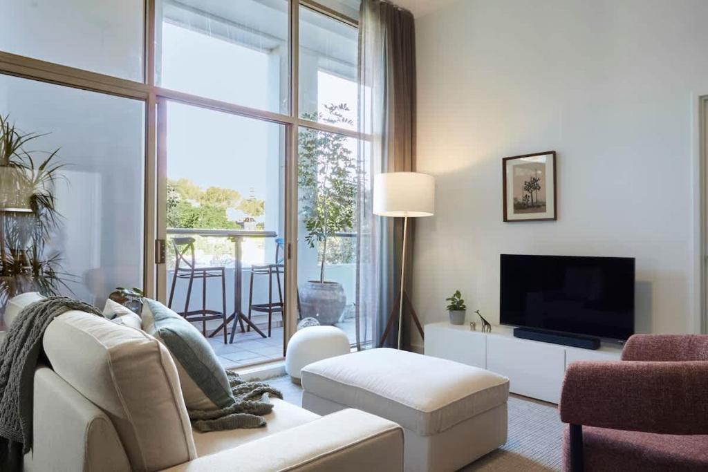 ein Wohnzimmer mit einer weißen Couch und einem großen Fenster in der Unterkunft Surry Hills Loft-Style Heritage 1BR - Indoor Pool, Sauna & Gym in Sydney