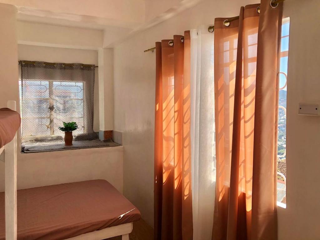 a room with a window with curtains and a bench at Elatap Studio Overlooking Baguio in Baguio