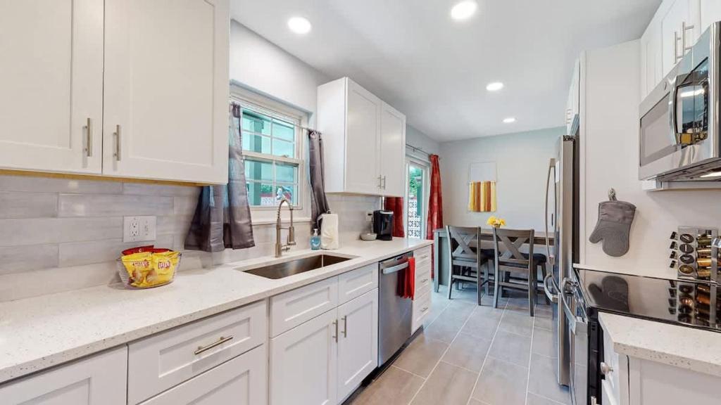 a kitchen with white cabinets and a sink and a table at Updated Family Unit with Two King Beds in Denver