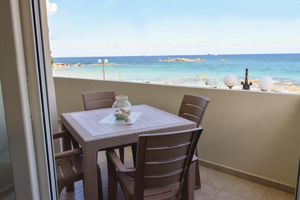 Una mesa y sillas con vista a la playa. en Lily of Crete 1 - Sea & Beach front Apartment, en Kalamaki