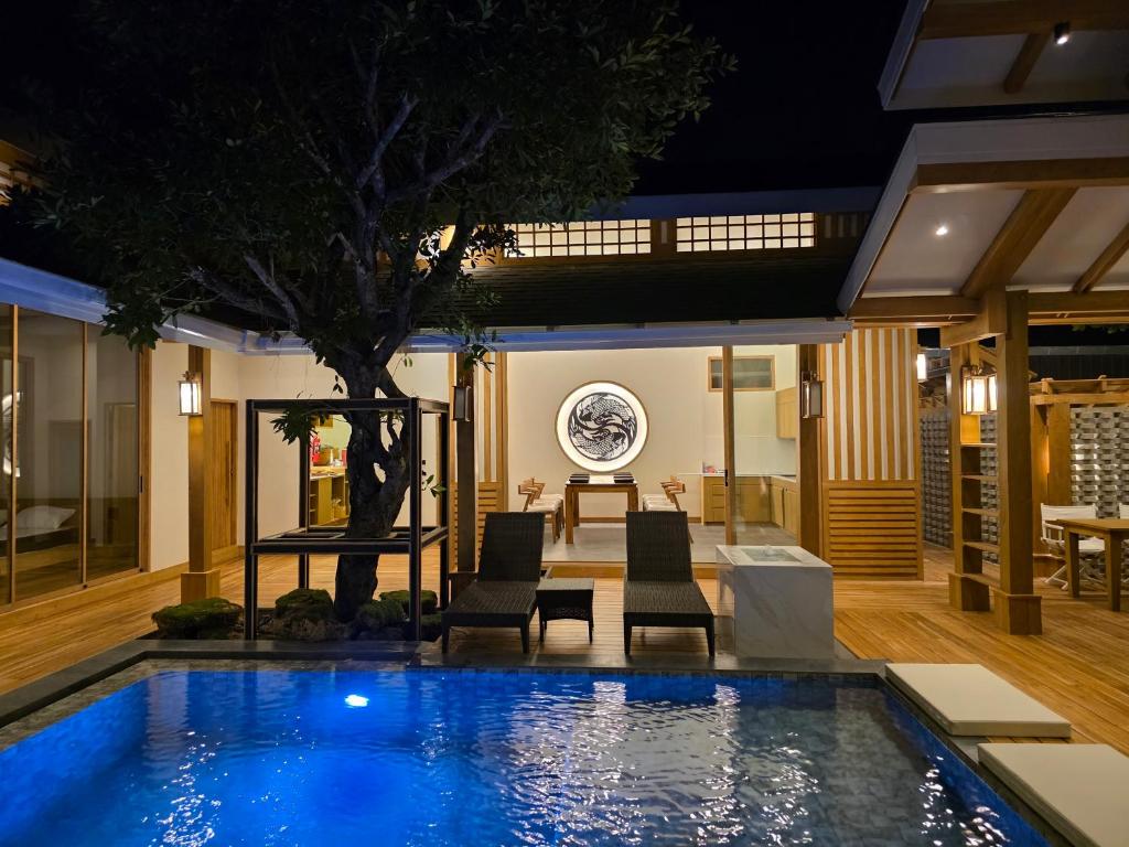 una piscina in una casa con sedie e un albero di Baan Prod Pool Villa Chiang Mai a Chiang Mai