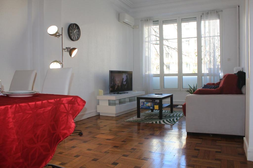 Una sala de estar con un sofá y un televisor en una pared. en LE REX Nice, en Niza