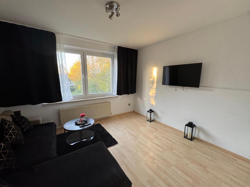 a living room with a black couch and a tv at HomeStay in Bochum