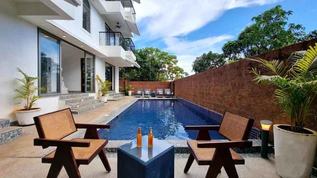 a backyard with a swimming pool and chairs and a house at Casa Pallazzo Luxury Villa - 10BHK Private Pool in Baga