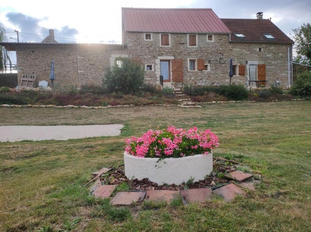 a pot of pink flowers in front of a house at Gîte rural au Bois des Riots in Montillot