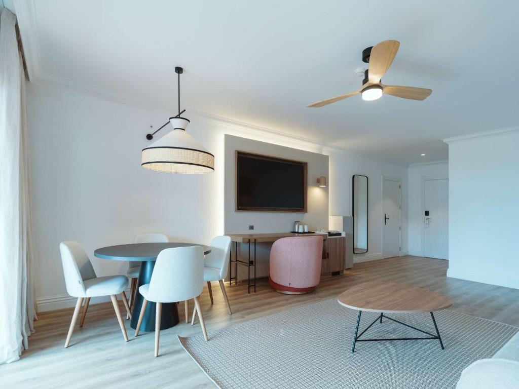 a living room with a table and chairs and a tv at Dreams Madeira Resort Spa & Marina in Caniçal