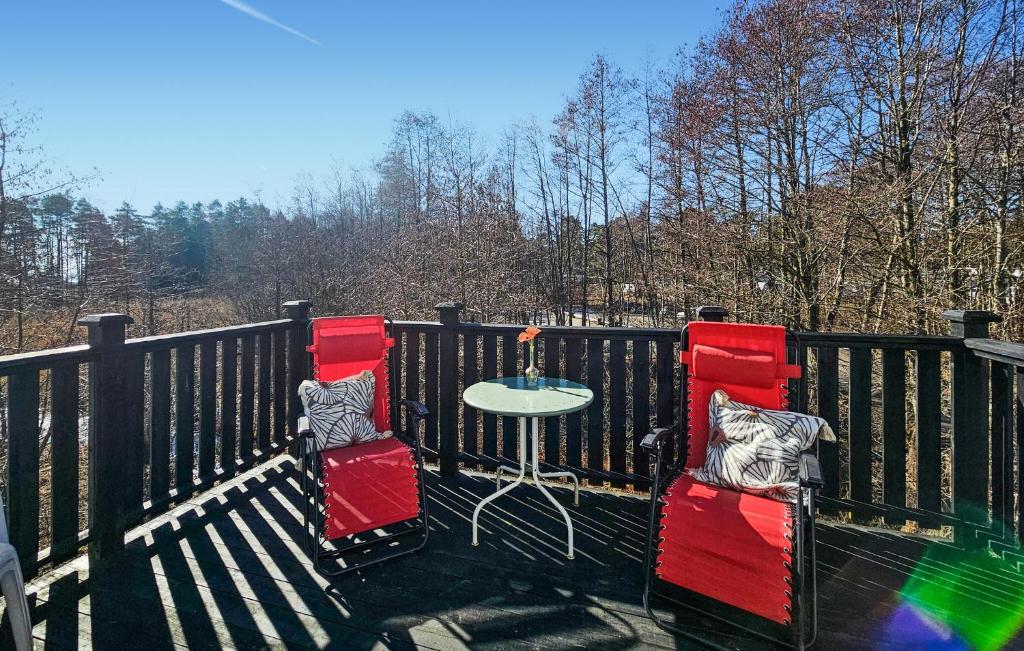 two red chairs and a table on a balcony at Cozy Apartment In Larkollen in Laurkollen