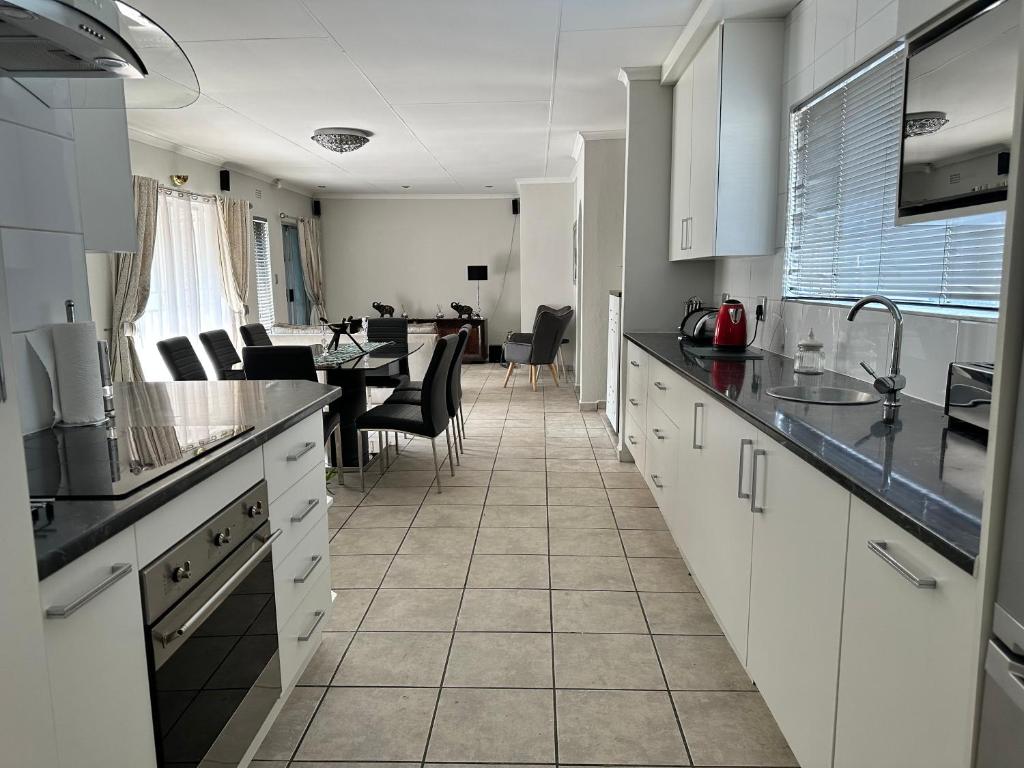 a kitchen with white cabinets and a dining room at AfriSky guest house in Kempton Park