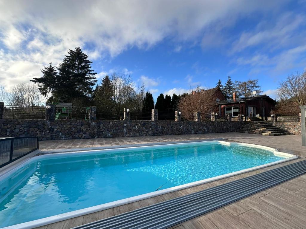 a swimming pool in a yard with a stone wall at Ferienhaus MILA - Pool, Sauna, Whirlwanne, 5000qm Privatgelände mit Bolzplatz in Striesdorf