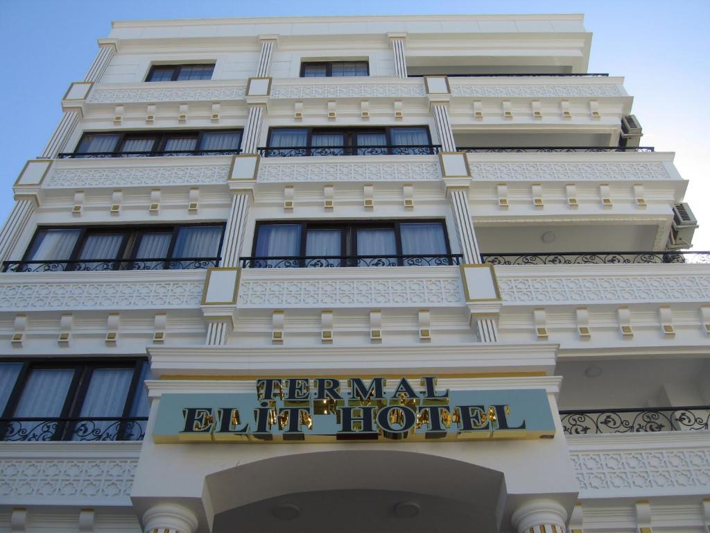 un grand bâtiment blanc avec un panneau sur celui-ci dans l'établissement Termal Elit Hotel, à Gokcedere