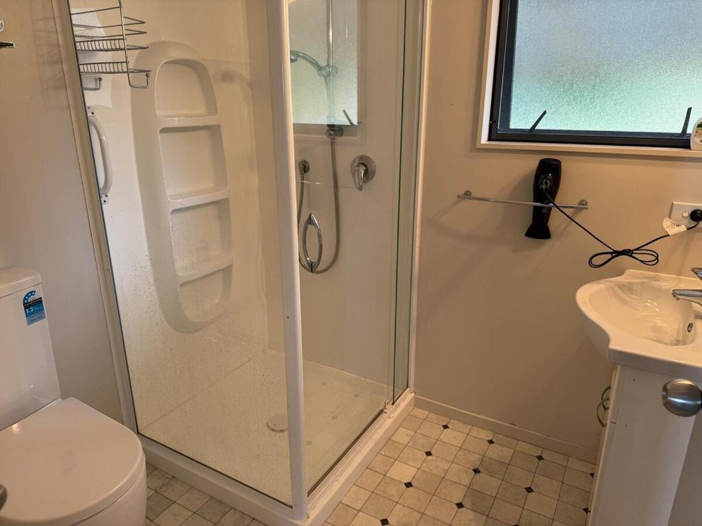 Un baño con ducha, inodoro y lavabo. en Cosy Country Private Cottage with views, en Harapepe