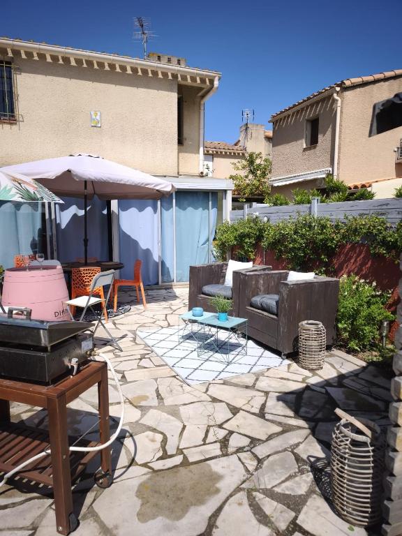 une terrasse en pierre avec un grill et un parasol dans l'établissement Maison grande terrasse proche du port St Cyprien, à Saint-Cyprien
