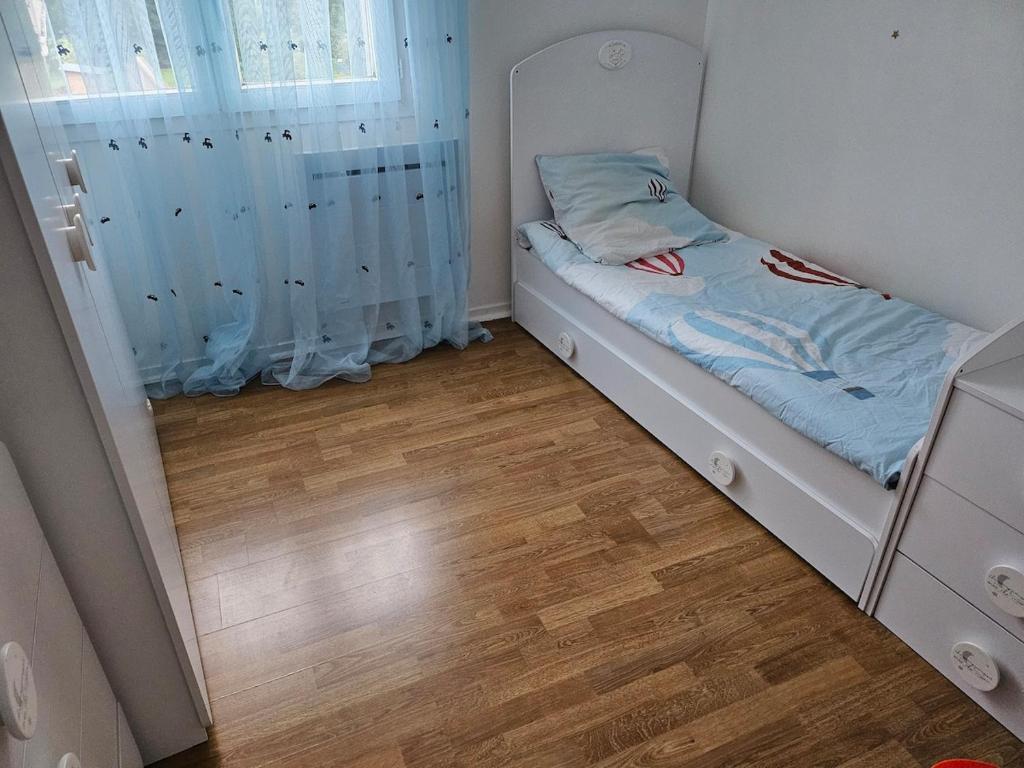 a small bed in a room with a wooden floor at Maison entiere avec Terrasse proche A1 CDG Asterix in Saint-Witz