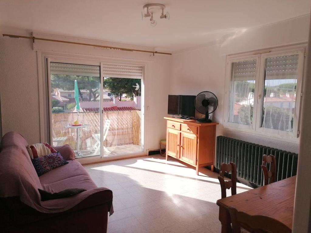 un salon avec un canapé et deux fenêtres dans l'établissement F2 Climatisé 800m de la Plage, à Canet