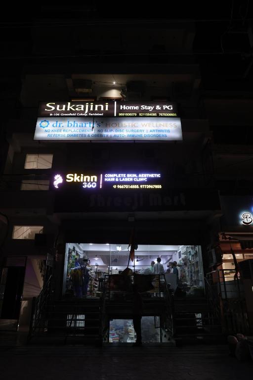a sign over the entrance to a store at night at Sukajini Home Stay & PG in Faridabad