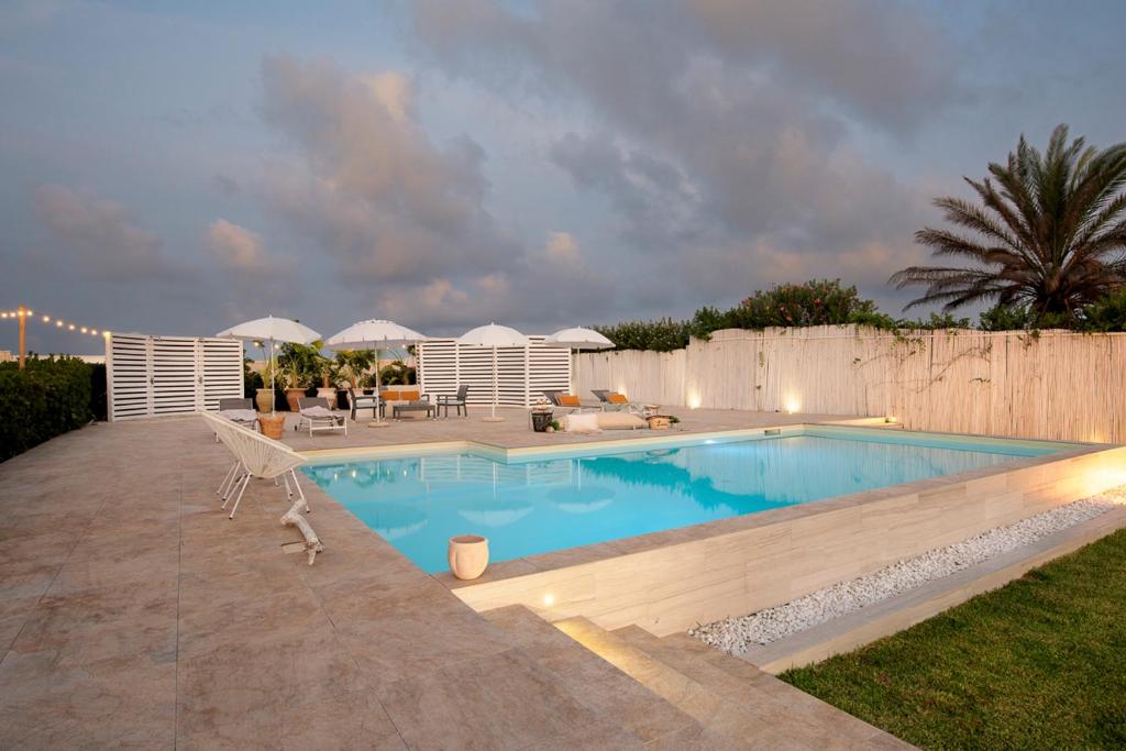 una piscina en un patio trasero con sombrillas en Villa Elysian con piscina privata, en Marzamemi