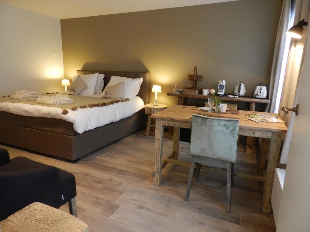 een slaapkamer met een bed, een tafel en een bureau bij B&B De Swaenhoeck in Damme
