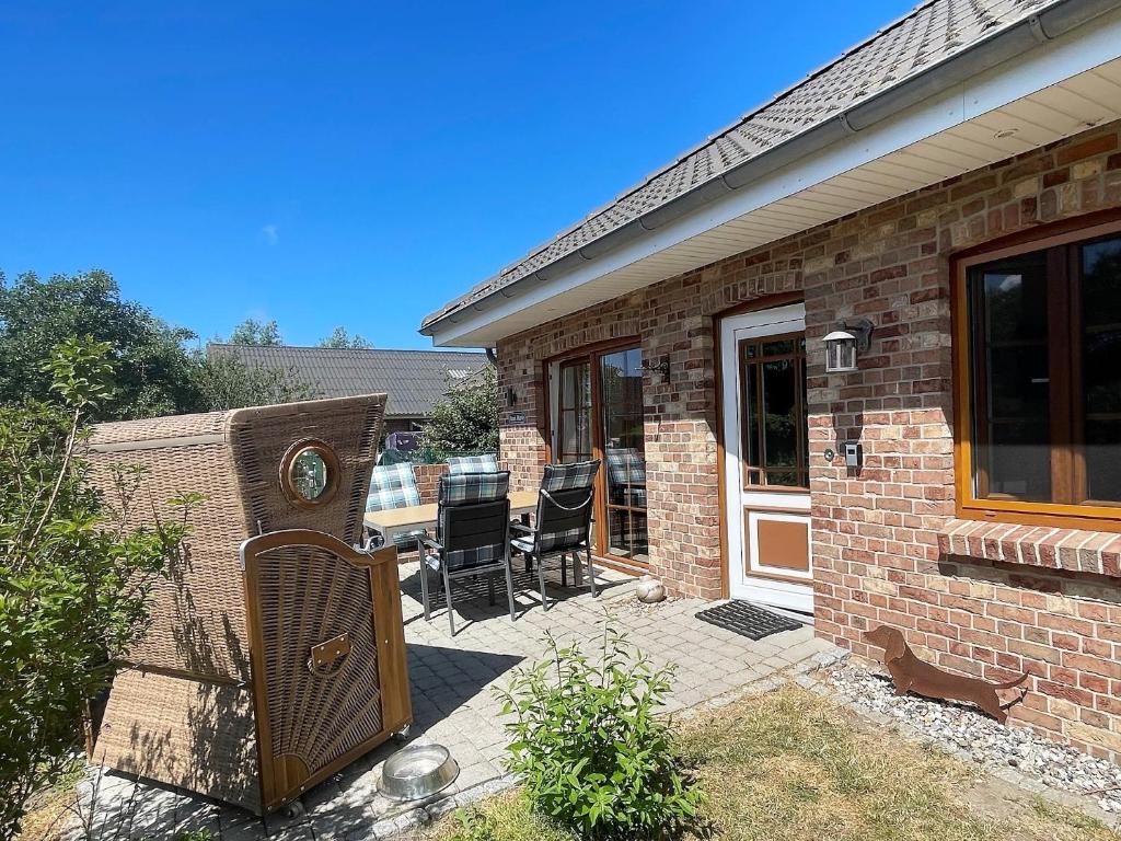 Cette maison en briques dispose d'une terrasse avec des chaises et une porte. dans l'établissement Ferienhaus Marie Rodenäs, à Rodenäs