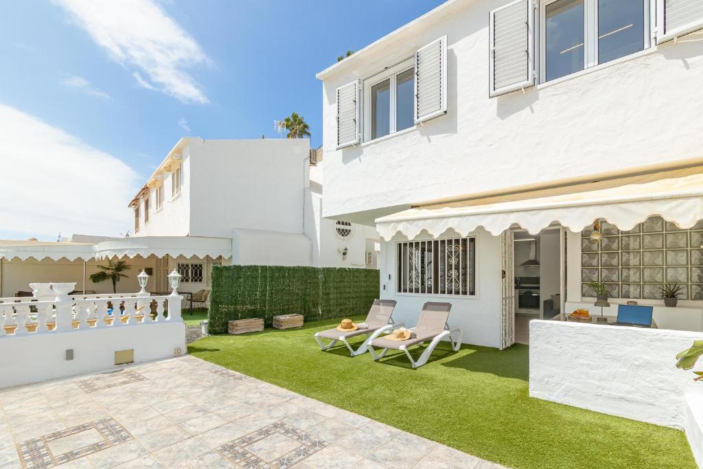 ein weißes Haus mit einem Garten mit grünem Gras in der Unterkunft HORIZON VACATION HOME - Yucatán Coastal Oasis in Mogán