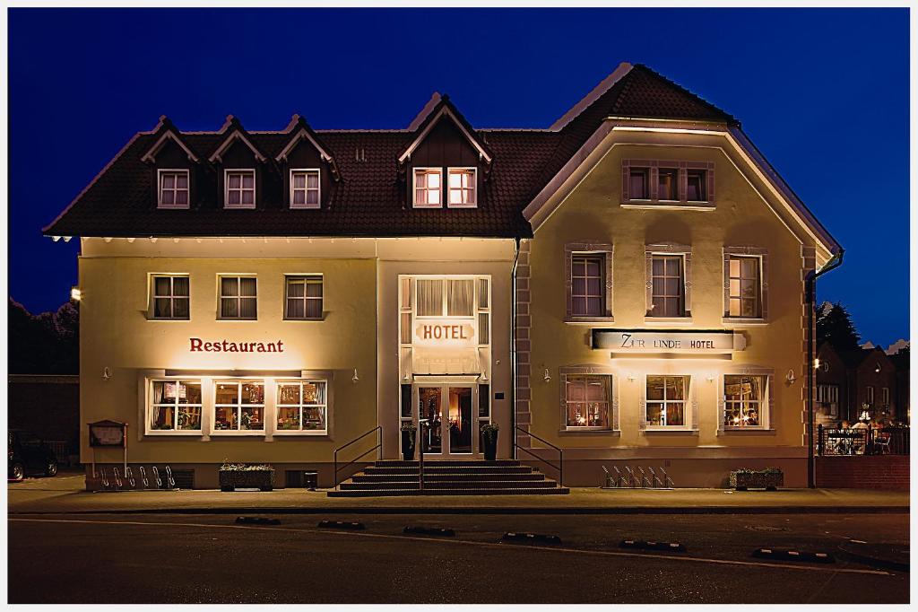 un grand bâtiment blanc dans une rue la nuit dans l'établissement Hotel Zur Linde, à Schermbeck