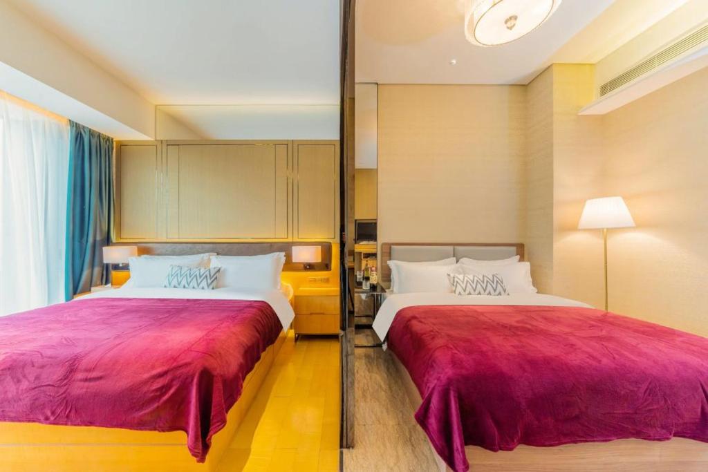 a hotel room with two beds with red sheets at Fa万濠国际服务公寓 in Guangzhou