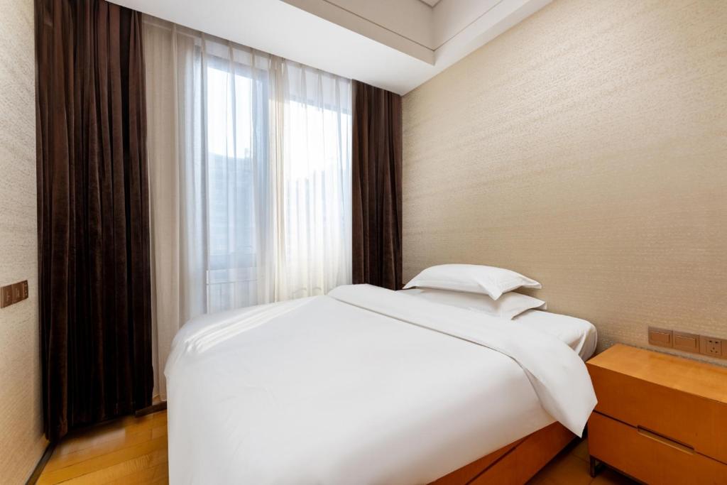 a white bed in a room with a window at Fa万濠国际服务公寓 in Guangzhou