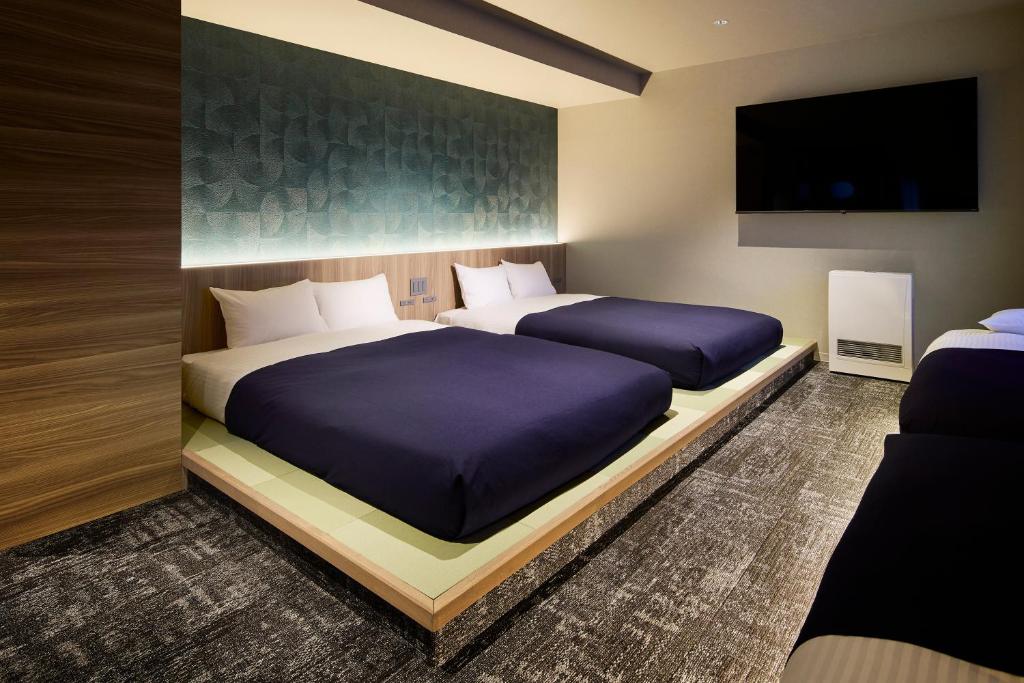 a bedroom with two beds and a flat screen tv at Minn Sapporo Odori W18 Station in Sapporo