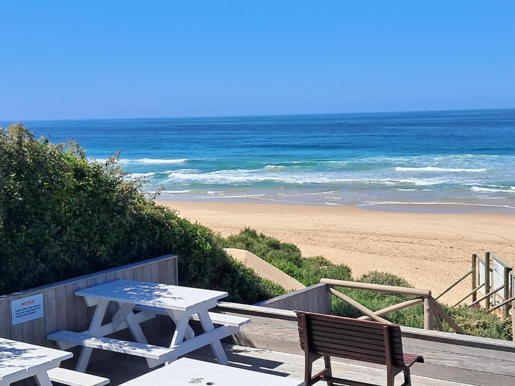 una mesa de picnic y un banco en la playa en Seaside Escape at The Dunes: Walk to Beach Braai, en Plettenberg Bay