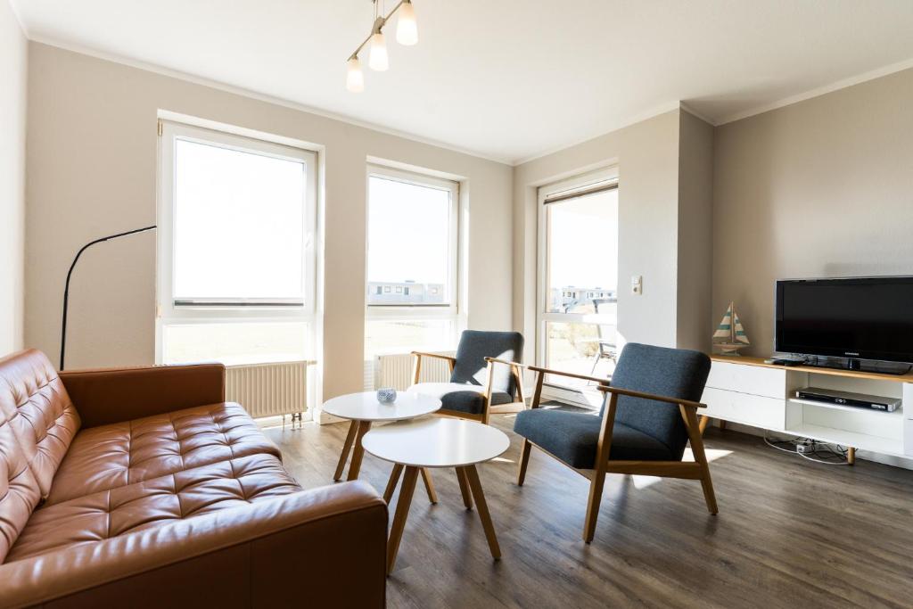 a living room with a couch and chairs and a tv at Fehmarnstrand 77 Whg 2 in Staberdorf