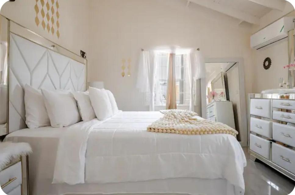 a white bedroom with a large white bed and a mirror at Barefoot Bliss Short Term Rental with pool in Colbeck Manor in Claremont